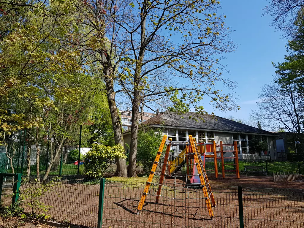 Aire de jeux clôturée avec une structure d’escalade orange