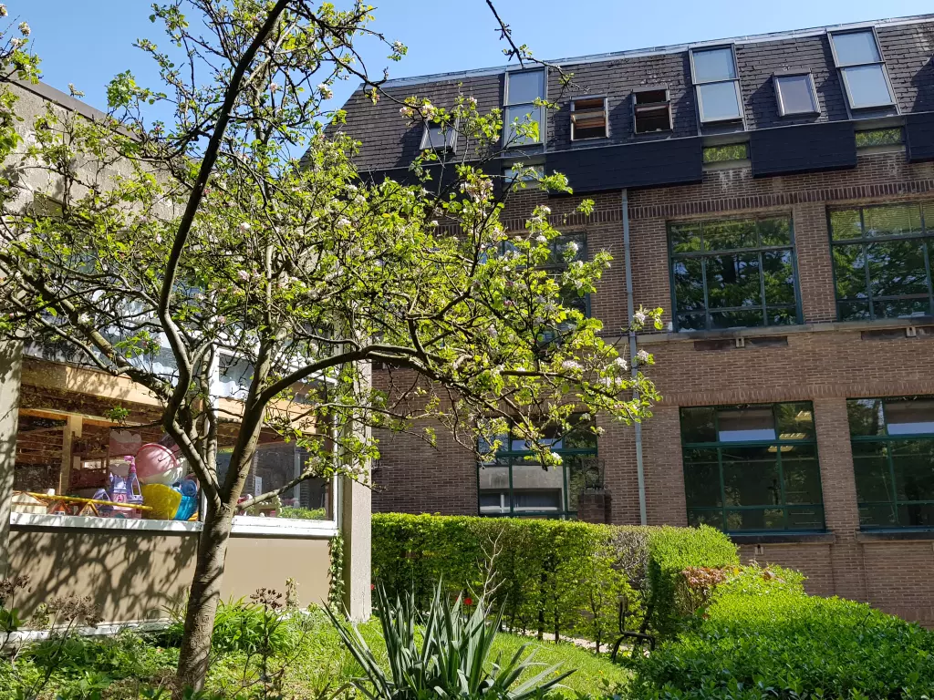 Bâtiment de briques avec un jardin fleuri au premier plan
