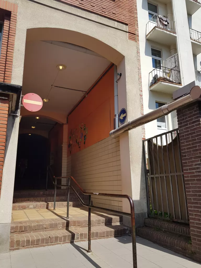 Entrée voûtée d’un bâtiment, avec un escalier et une rampe