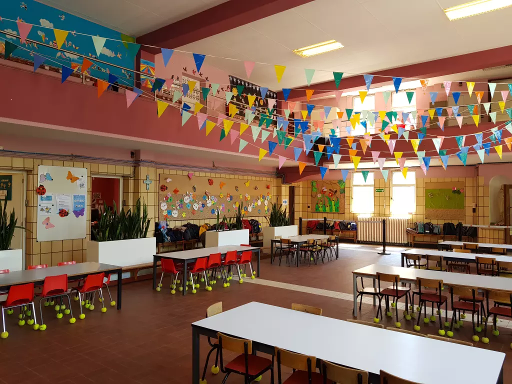 Grande salle décorée de fanions, avec des tables et des chaises