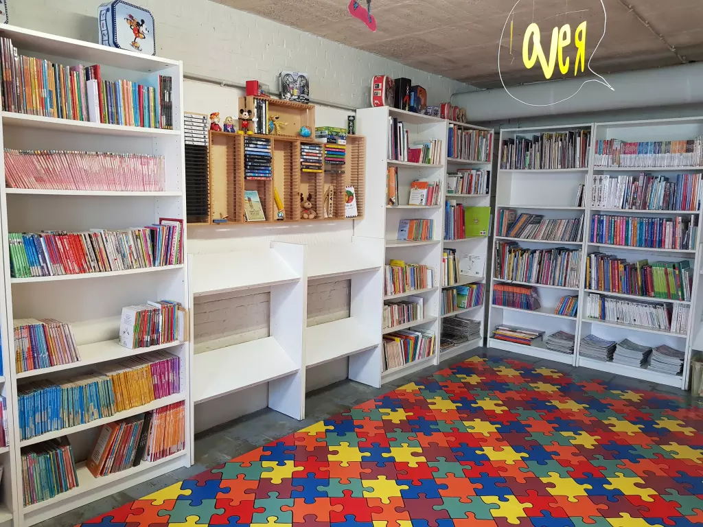 Bibliothèque avec des étagères de livres et un tapis puzzle coloré