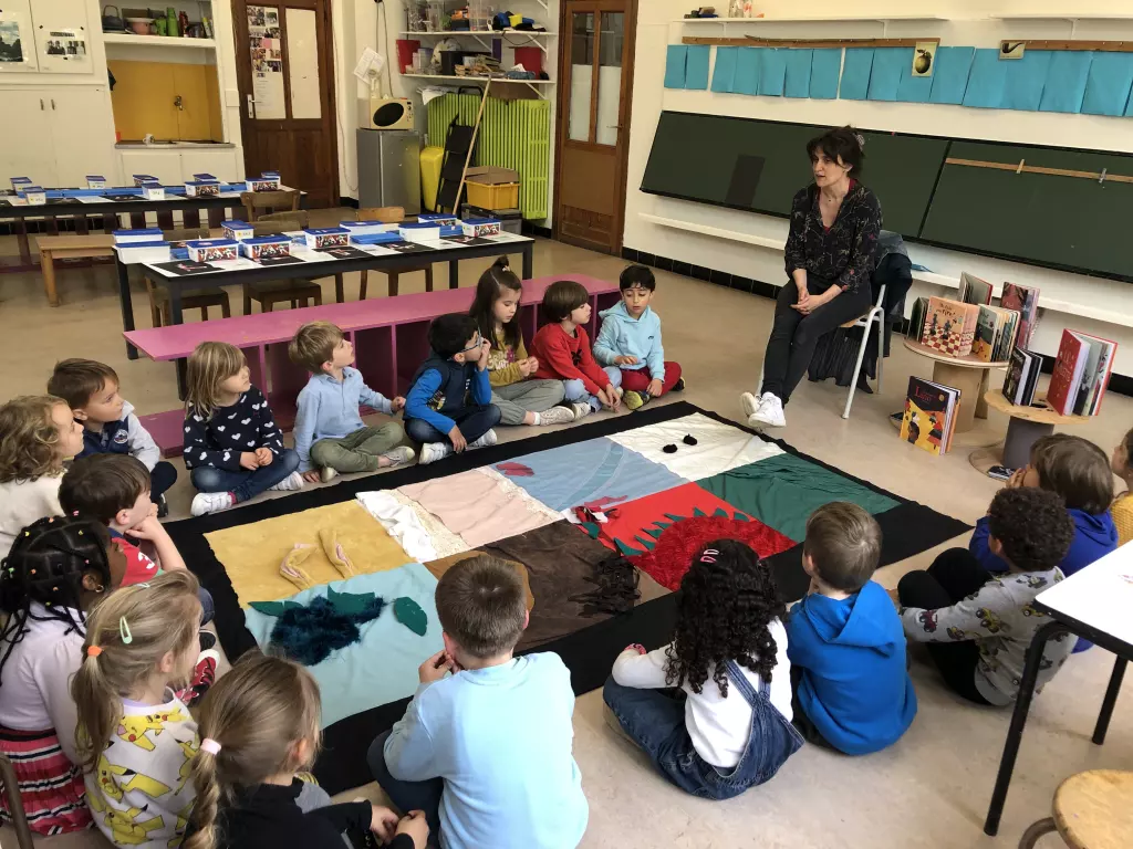 Une enseignante lit une histoire aux enfants de maternelle assis autour d’un tapis