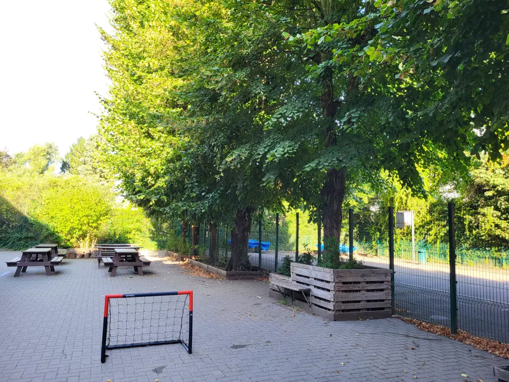 Cour ombragée avec un petit but de football et des tables de pique-nique