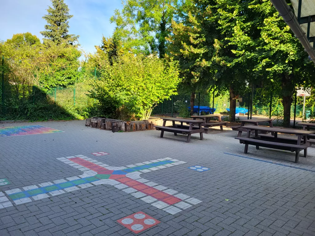 Jeux peints au sol de la cour et tables de pique-nique sous les arbres