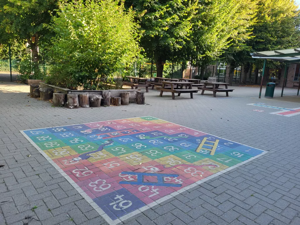 Grand jeu de l’oie peint au sol, devant des tables de pique-nique