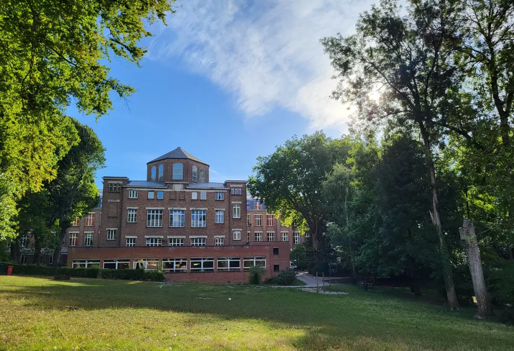 Le bâtiment de l’école vu depuis la pelouse du parc