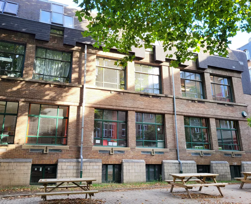 Façade de briques et tables de pique-nique au pied du bâtiment