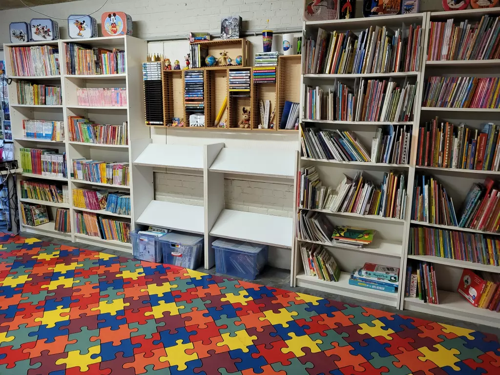Coin lecture de l’école, avec des bibliothèques remplies de livres et un tapis puzzle